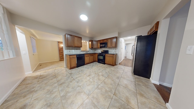 kitchen featuring decorative backsplash, light tile patterned floors, sink, and black appliances