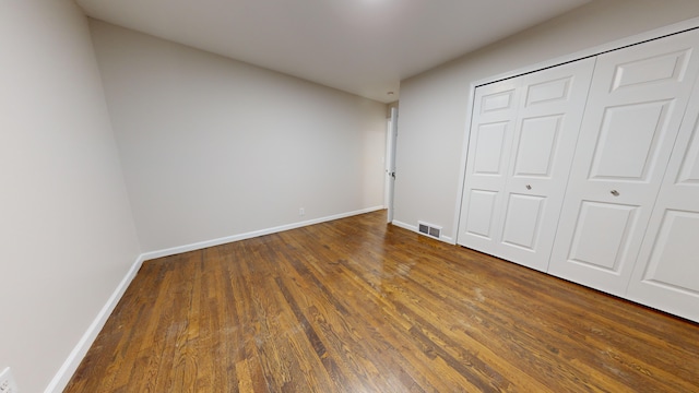 unfurnished bedroom featuring dark hardwood / wood-style flooring and a closet