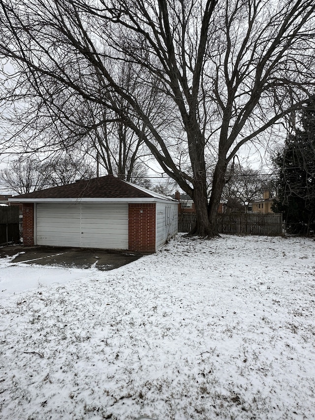 yard covered in snow featuring a garage and an outdoor structure