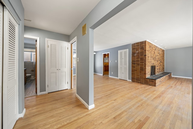 unfurnished living room with a fireplace and light wood-type flooring