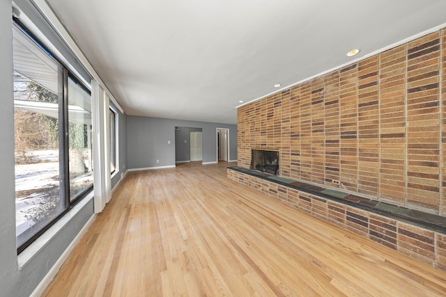 unfurnished living room with a brick fireplace and light hardwood / wood-style flooring