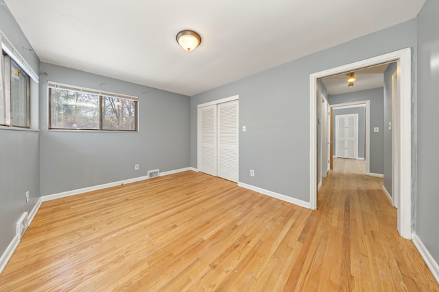 unfurnished bedroom featuring light wood-type flooring and a closet