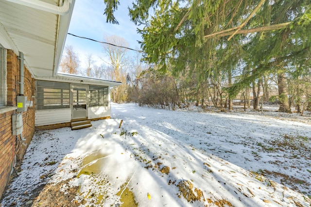 yard layered in snow featuring a sunroom