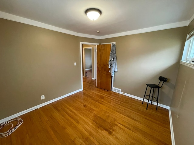 empty room featuring hardwood / wood-style floors and crown molding