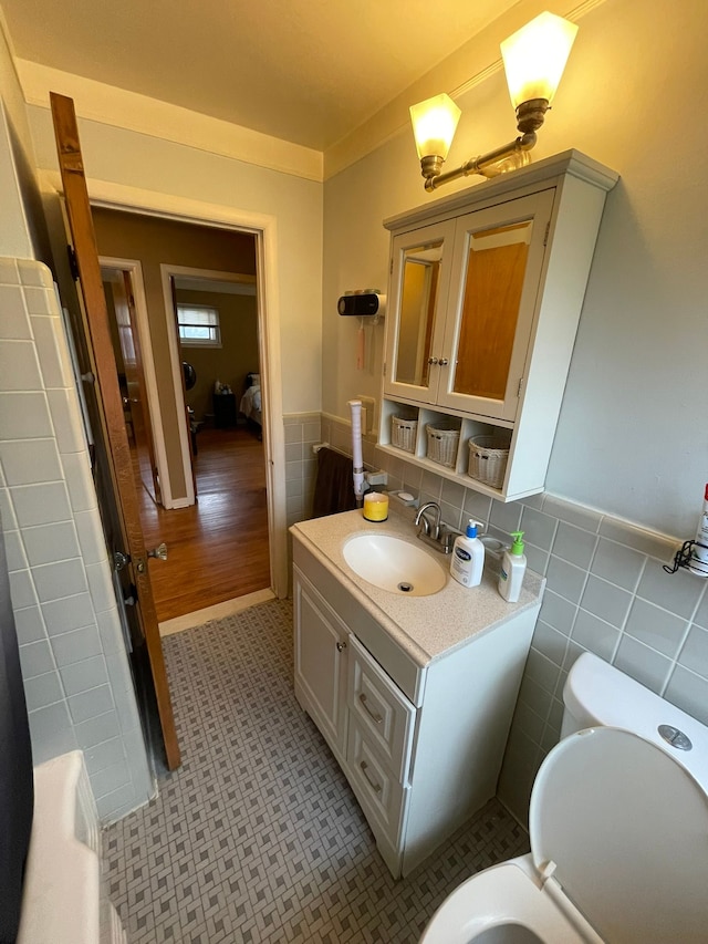 bathroom with vanity, tile patterned floors, crown molding, toilet, and tile walls