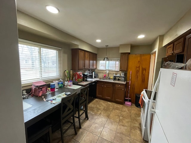 kitchen with pendant lighting, backsplash, white refrigerator, light tile patterned floors, and black dishwasher