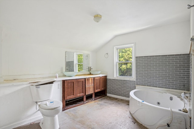 bathroom with vanity, vaulted ceiling, tile walls, toilet, and a tub