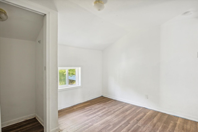 additional living space with light hardwood / wood-style flooring and lofted ceiling