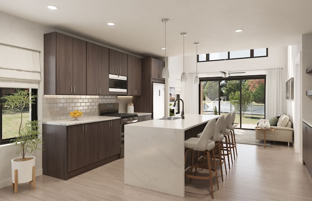 kitchen with sink, hanging light fixtures, light hardwood / wood-style flooring, dark brown cabinetry, and stainless steel appliances