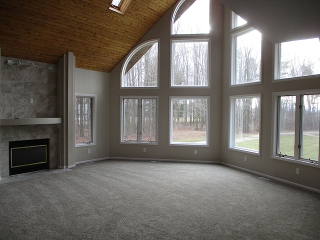 unfurnished living room featuring carpet, a tile fireplace, and wood ceiling