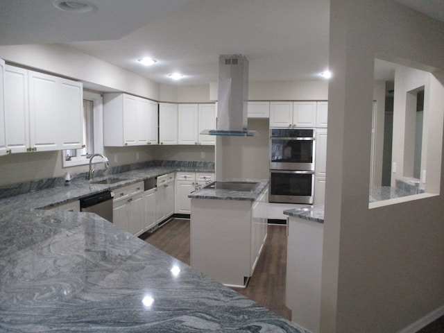 kitchen featuring appliances with stainless steel finishes, dark stone counters, extractor fan, a kitchen island, and white cabinetry