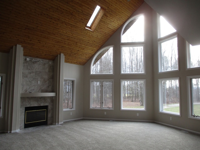 unfurnished living room featuring wood ceiling, light colored carpet, a towering ceiling, and a high end fireplace