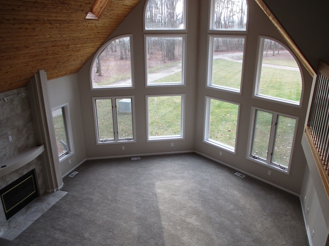 unfurnished living room with carpet, wood ceiling, high vaulted ceiling, and a tiled fireplace