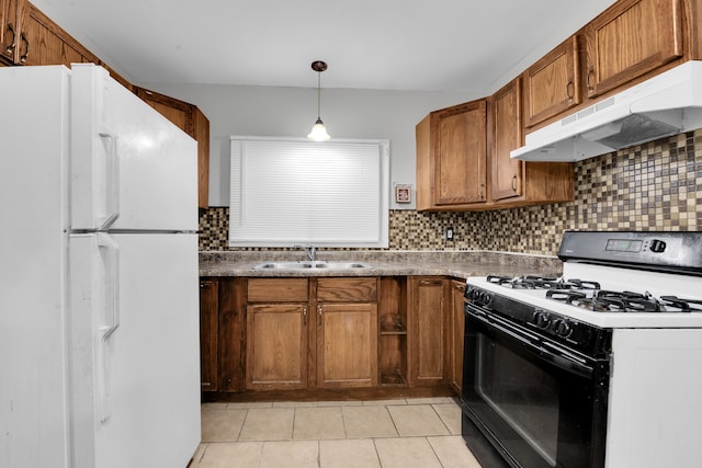 kitchen with backsplash, white refrigerator, sink, hanging light fixtures, and gas range oven