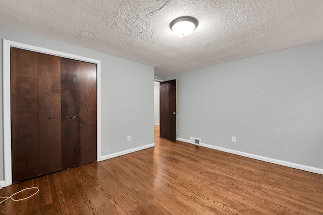 unfurnished bedroom with wood-type flooring, a textured ceiling, and a closet