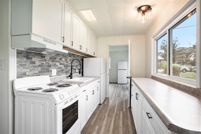 kitchen with white cabinets, white appliances, sink, and hardwood / wood-style flooring