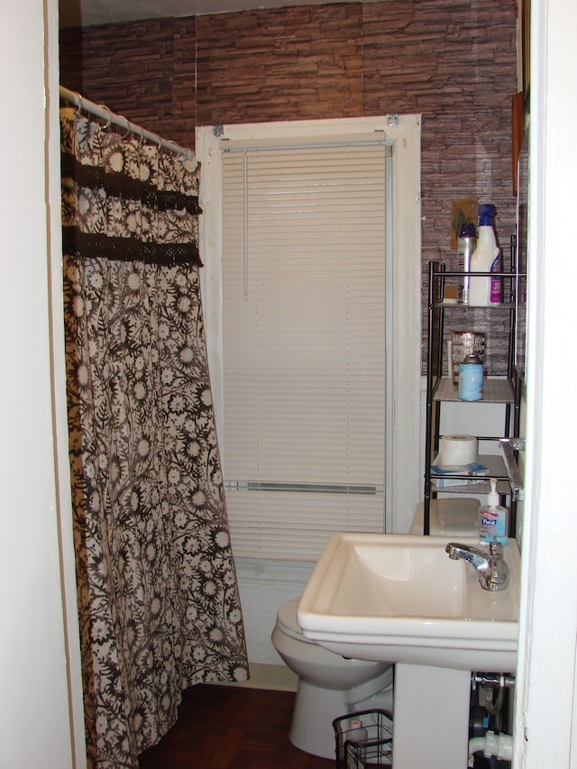 bathroom featuring wood walls, sink, and toilet