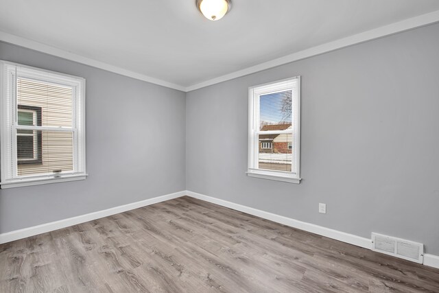 spare room featuring light hardwood / wood-style floors, a wealth of natural light, and ornamental molding