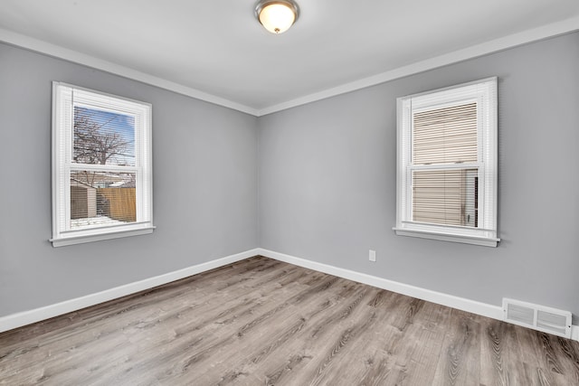 spare room featuring ornamental molding and light hardwood / wood-style flooring