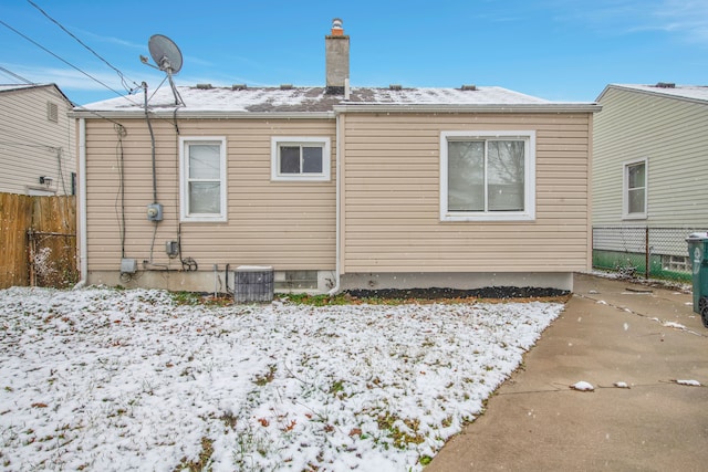 snow covered rear of property featuring cooling unit