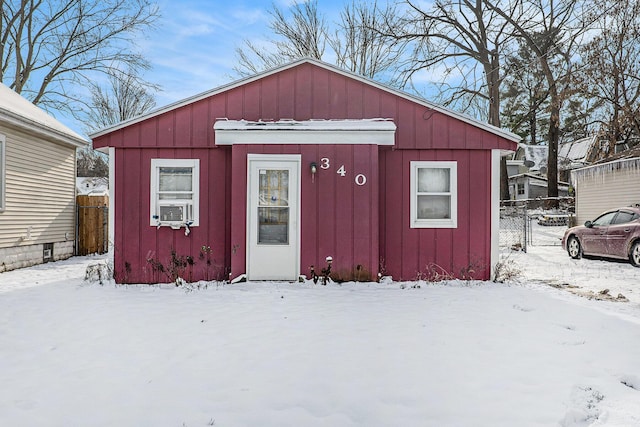 snow covered structure featuring fence and cooling unit