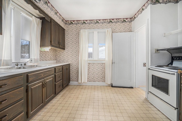 928 Phoenix St, South Haven, MI 49090 - kitchen with range with electric stovetop, wallpapered walls, a sink, dark brown cabinetry, and plenty of natural light