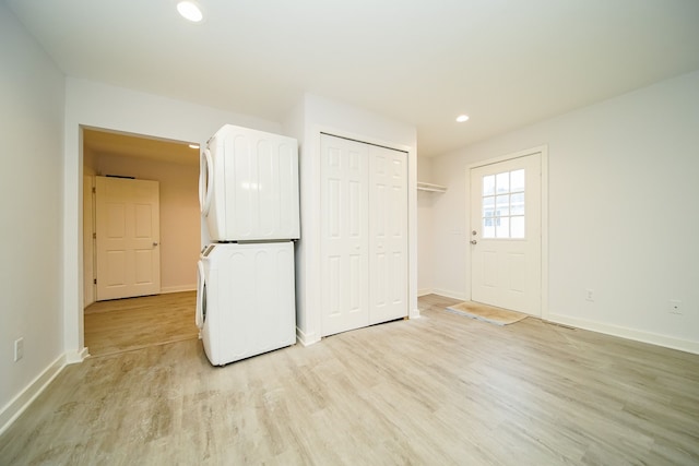 interior space featuring white cabinetry, light hardwood / wood-style flooring, and stacked washer and clothes dryer