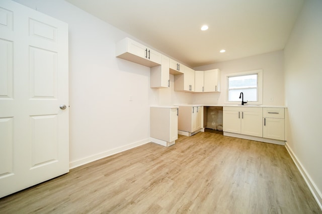 kitchen with light hardwood / wood-style flooring, white cabinetry, and sink