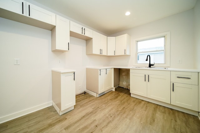 kitchen with white cabinets, light hardwood / wood-style floors, and sink