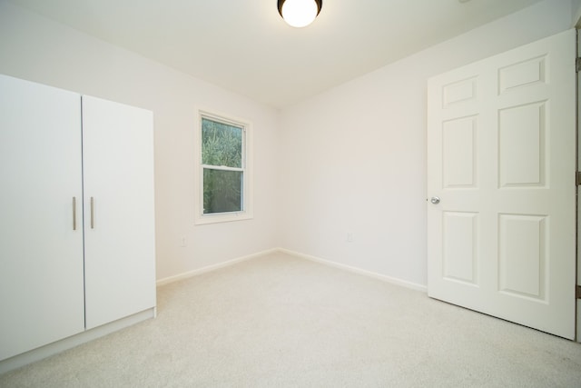 unfurnished bedroom featuring light carpet and a closet