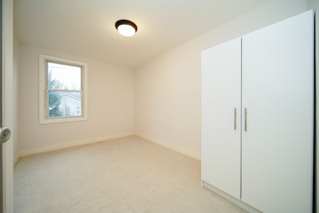 unfurnished bedroom with light carpet and a closet