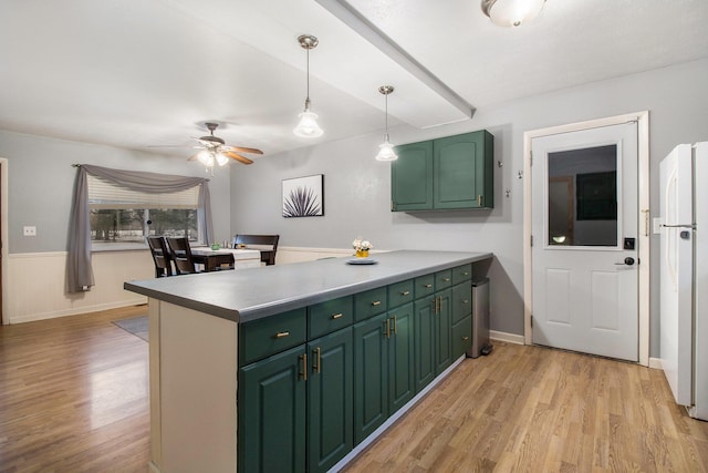 kitchen with light wood finished floors, freestanding refrigerator, a peninsula, hanging light fixtures, and green cabinets