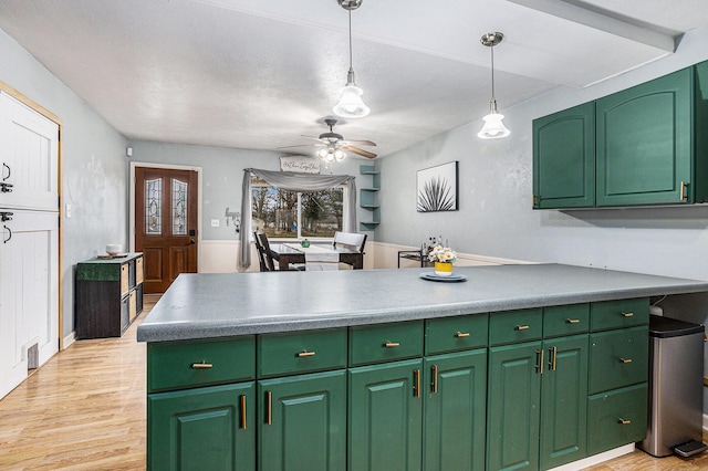 kitchen with ceiling fan, a peninsula, hanging light fixtures, light wood-style floors, and green cabinets