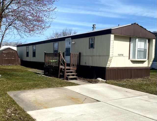 manufactured / mobile home with a front yard and a storage shed