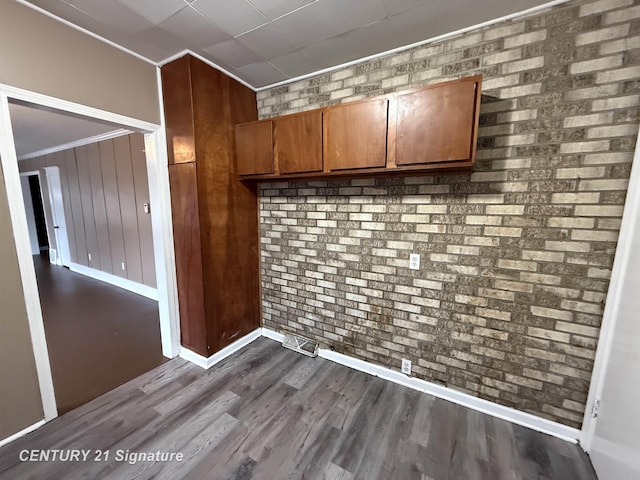 kitchen featuring crown molding, wooden walls, brick wall, and hardwood / wood-style flooring