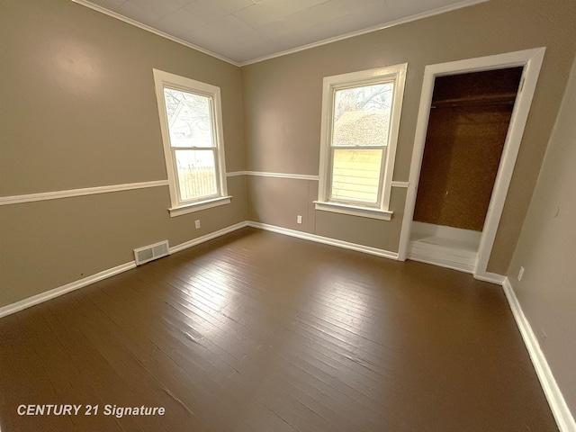 spare room with crown molding and dark wood-type flooring