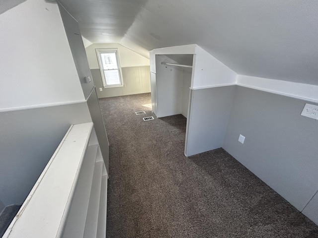 additional living space with dark colored carpet and lofted ceiling