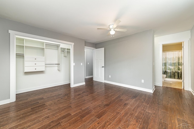 unfurnished bedroom with a closet, ceiling fan, dark wood-type flooring, and ensuite bathroom