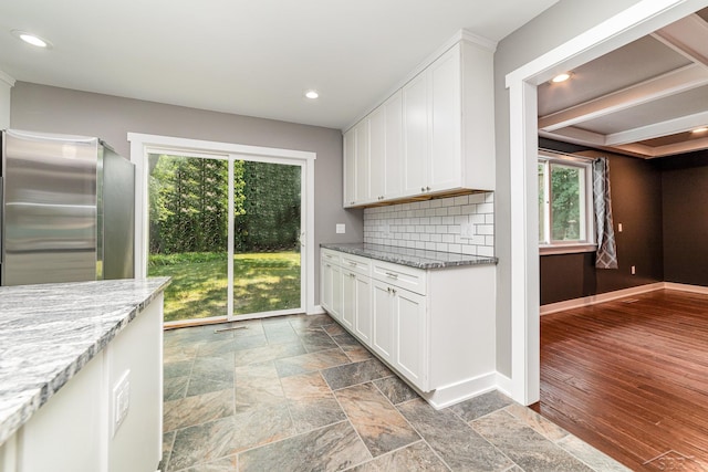 kitchen with stainless steel fridge, white cabinetry, light hardwood / wood-style floors, and light stone counters