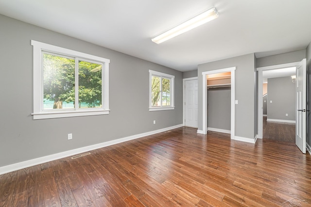 unfurnished bedroom featuring a walk in closet and hardwood / wood-style floors