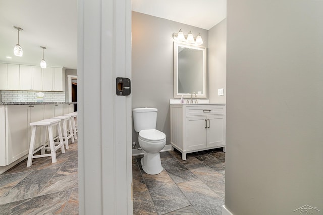 bathroom featuring vanity, tasteful backsplash, and toilet