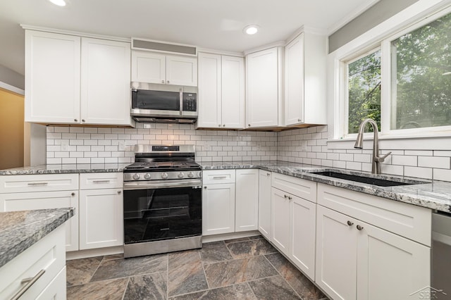 kitchen with light stone counters, sink, white cabinetry, and stainless steel appliances