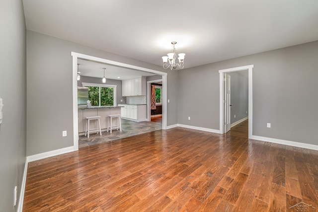 unfurnished living room featuring dark hardwood / wood-style flooring and a chandelier