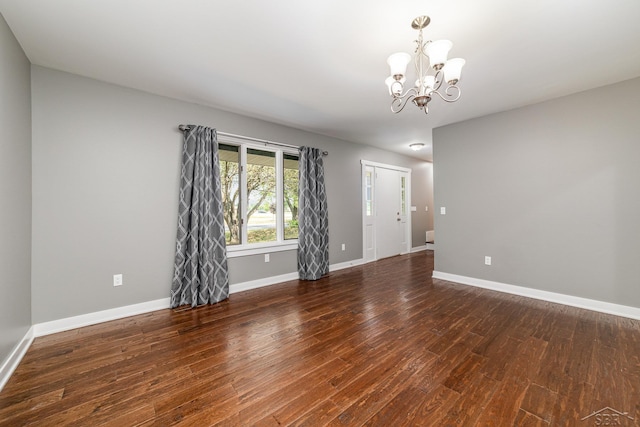 empty room featuring dark hardwood / wood-style flooring and an inviting chandelier