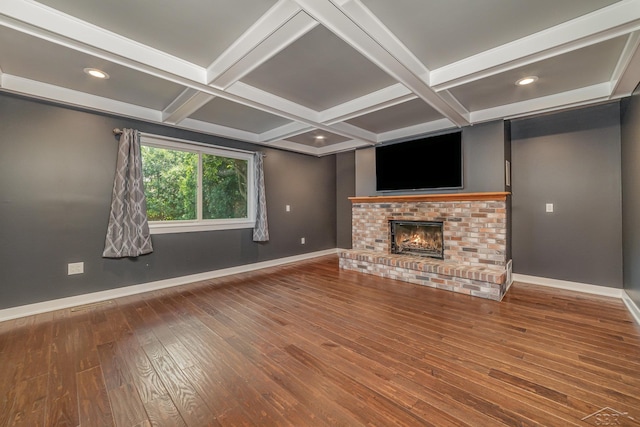 unfurnished living room featuring beam ceiling, wood-type flooring, coffered ceiling, and a brick fireplace