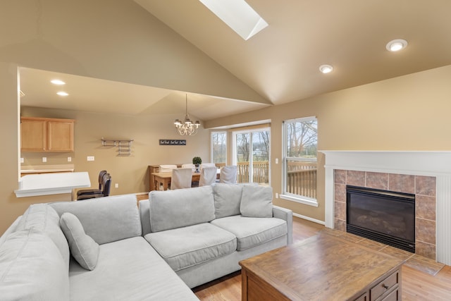 living room featuring a tile fireplace, light wood-type flooring, a chandelier, and high vaulted ceiling