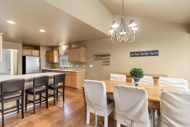 dining area featuring light hardwood / wood-style floors, sink, and an inviting chandelier