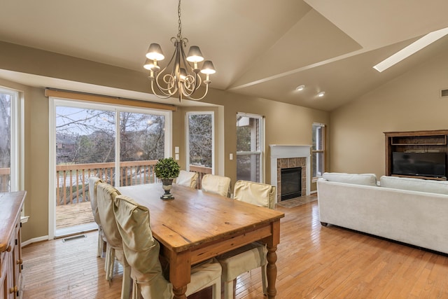 dining room with a fireplace, lofted ceiling, and light wood-type flooring