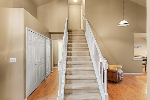 stairs with high vaulted ceiling and hardwood / wood-style flooring