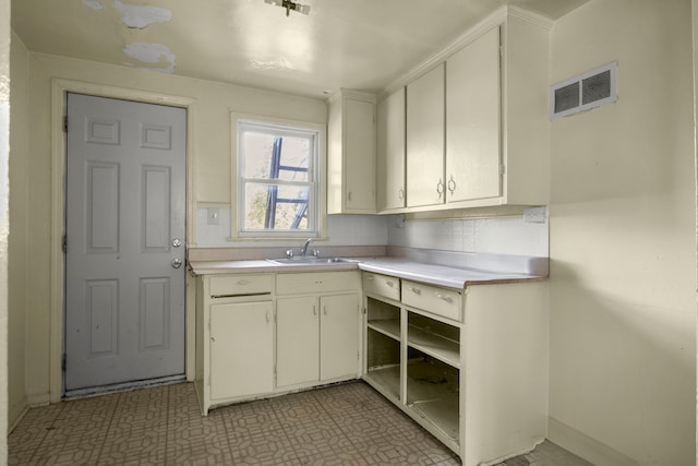 kitchen featuring decorative backsplash, white cabinetry, and sink